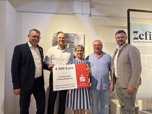 Personen halten großen Spendenscheck hoch.